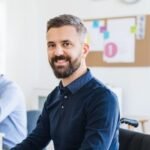 demo-attachment-88-young-businessman-in-wheelchair-with-colleagues-EWTN4AC